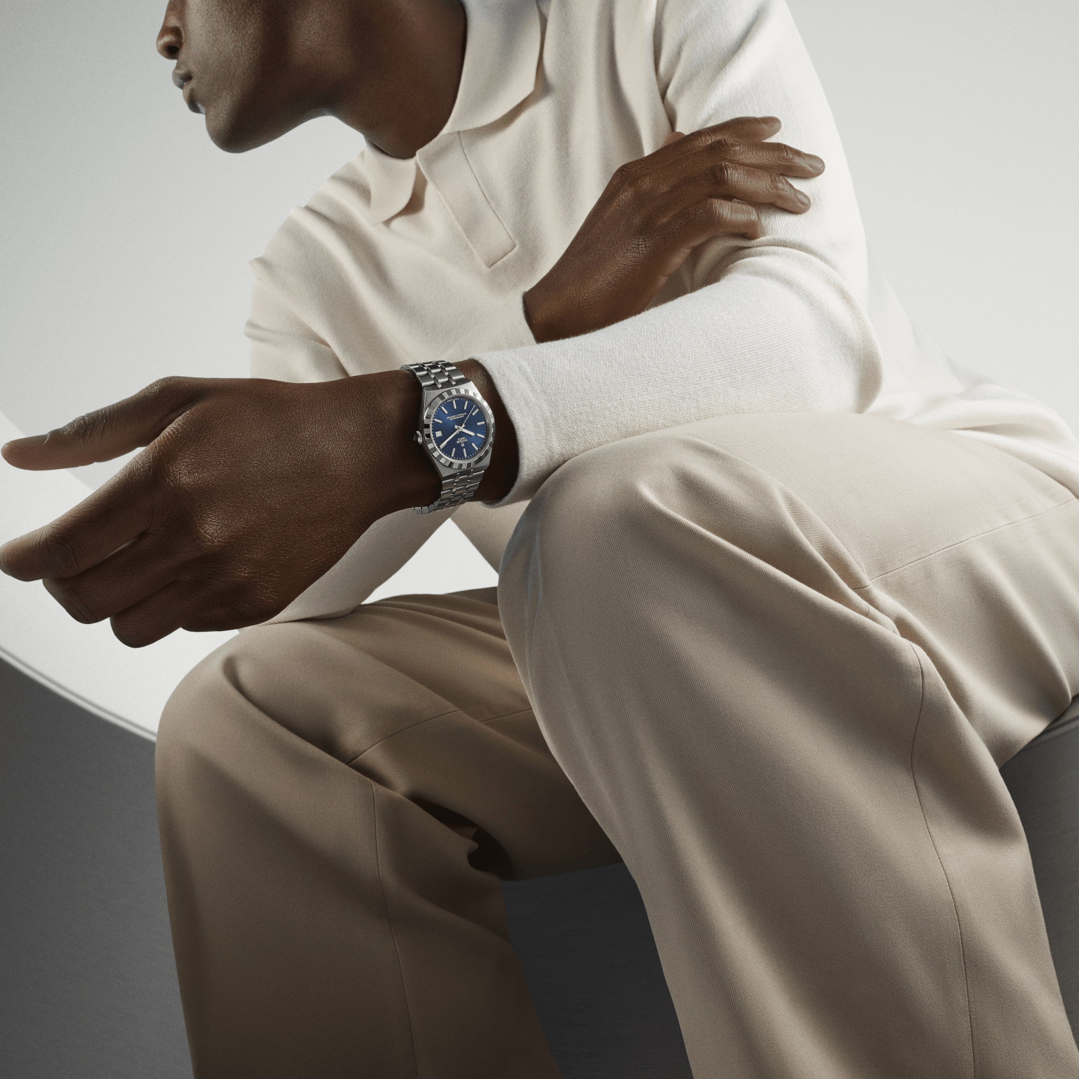 A black man in a cream coloured oxford and khakis wearing a Tudor Royal reference M2836C1A0-0102 in stainless steel with stunning blue dial.