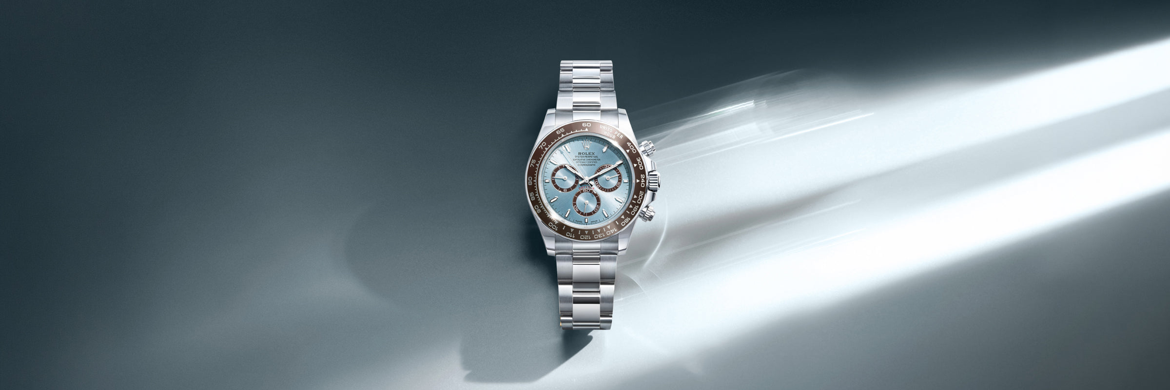 Rolex Cosmograph Daytona in solid platinum with an ice blue dial and chestnut brown Cerachrom bezel, set against a reflective surface