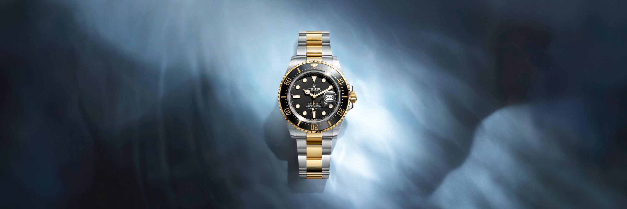 Rolex Sea-Dweller in yellow Rolesor with a black dial, set against a blue, rippling background