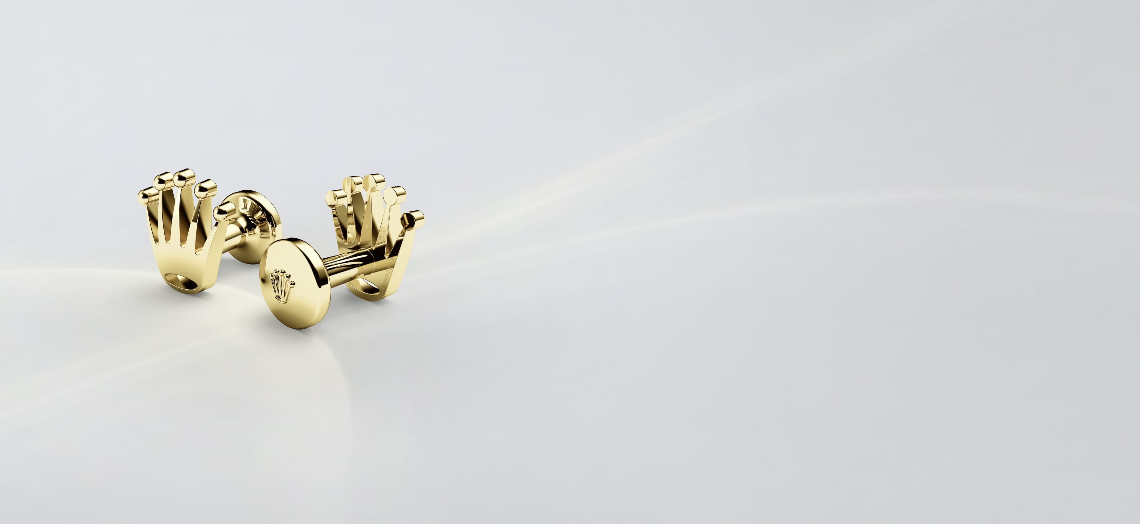 Gold Rolex Crown Cufflinks on a Light Grey Background