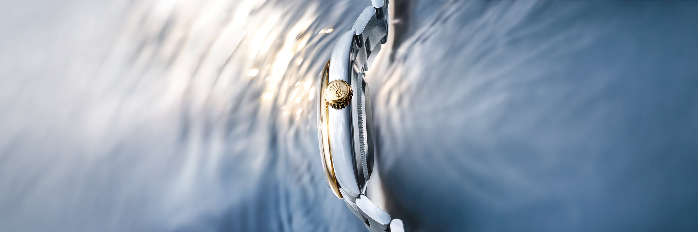 Profile of a Rolex Oyster Perpetual 41 in yellow Rolesor, with rippling water in the background.